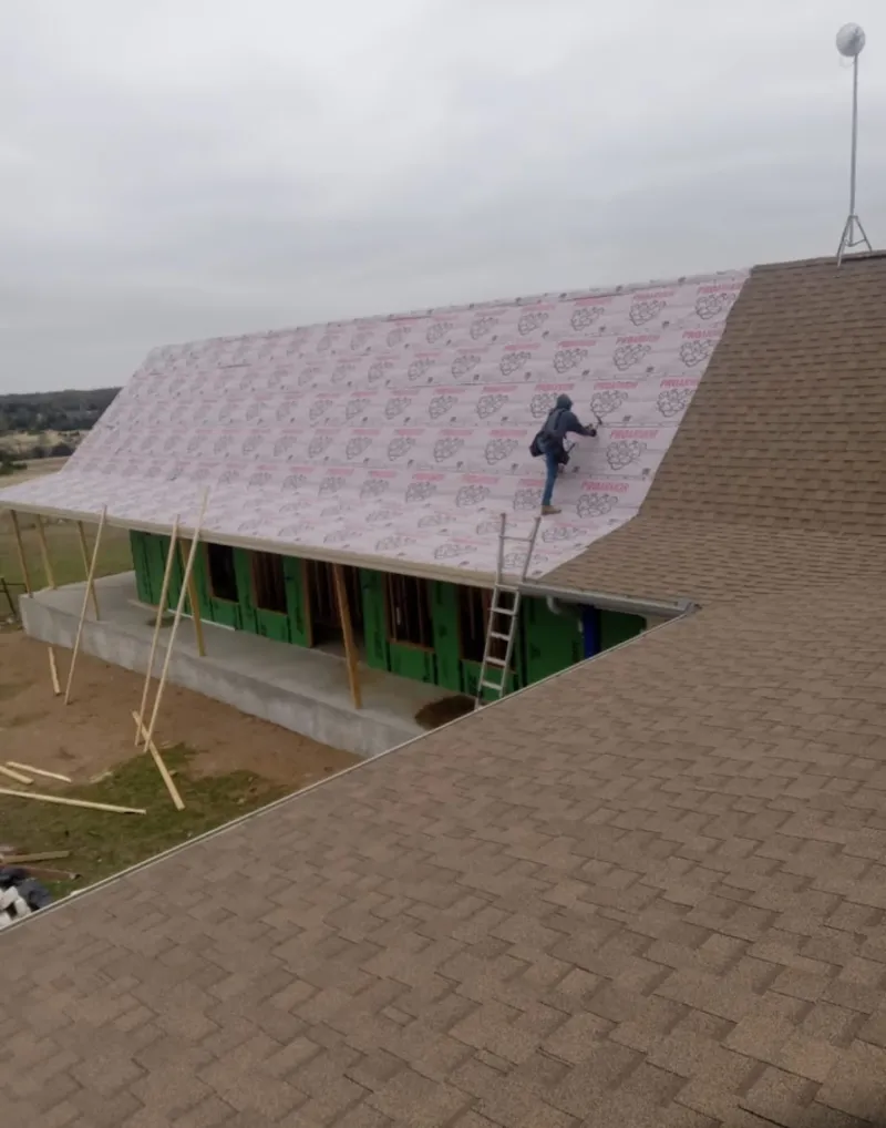 Worker preparing underlayment for a metal roof installation in Nutley